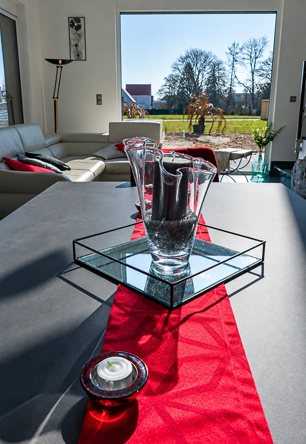 Table moderne avec chemin rouge et vase en verre dans un salon lumineux